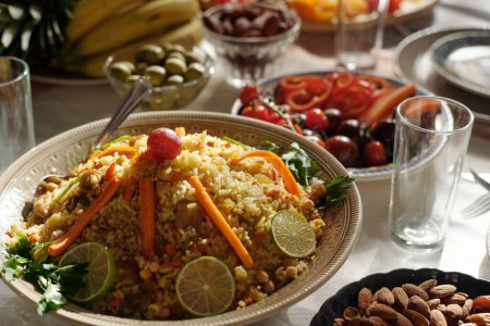 Selective focus closeup of pilaf decorated with slices of lime, carrot and grape on festive table prepared for Eid Al-Fitr celebration