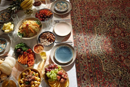 Foto de Desde arriba no hay gente disparada de abundante mesa festiva servida para la celebración de Uraza Bayram en majilis con alfombra oriental en el suelo - Imagen libre de derechos