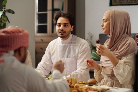 Foto de Sobre el hombro de un joven musulmán hablando con miembros de la familia mientras cenaba festivamente en Uraza Bayram - Imagen libre de derechos