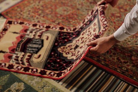 Foto de Manos en el hombre musulmán irreconocible colocando alfombra de oración en el suelo en la sala de estar en casa, espacio para copiar - Imagen libre de derechos
