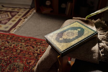 No people high angle of holy Quran book in green hard cover decorated with gold ornaments lying in living room