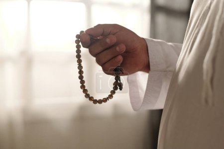 Closeup of unrecognizable Muslim man holding misbaha beads in hand, copy space
