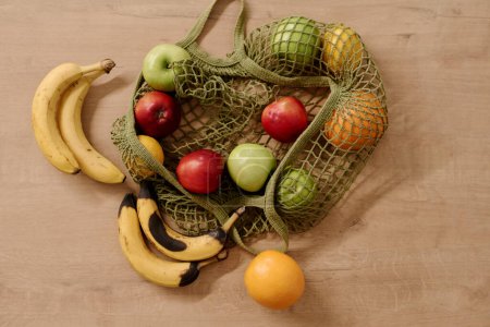 Foto de Vista superior de la bolsa de compras con surtido de frutas que incluyen plátanos en mal estado y frescos, manzanas verdes y rojas maduras y naranjas jugosas - Imagen libre de derechos