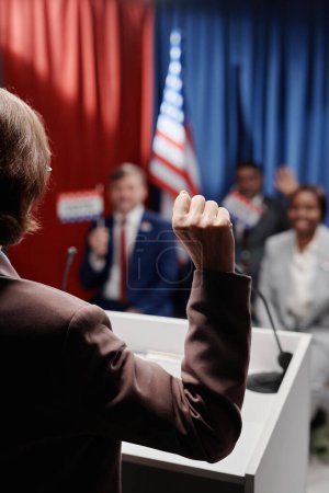 Photo for Rear view of mature female politician making convincing gesture in front of public during speech at voting campaign or conference - Royalty Free Image