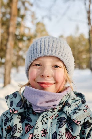 Photo for Close-up portrait of pretty girl with blond hair and blue eyes looking at camera with smile while enjoying winter day in park - Royalty Free Image
