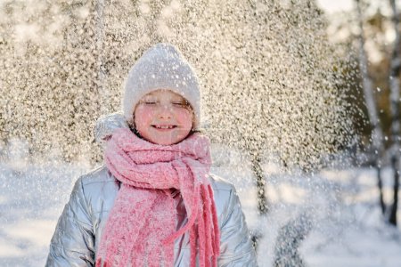 Téléchargez les photos : Jolie fille joyeuse en vêtements d'hiver chauds profitant de chutes de neige tout en se tenant dans l'environnement naturel le week-end d'hiver - en image libre de droit