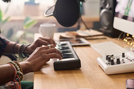Foto de Vista lateral de las manos de un joven músico tocando las teclas del sintetizador electrónico mientras crea y graba nueva música en el estudio - Imagen libre de derechos