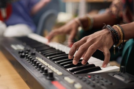 Téléchargez les photos : Hand of young unrecognizable male musician pressing keys of electronic synthesizer while composing, performing and recording his music - en image libre de droit