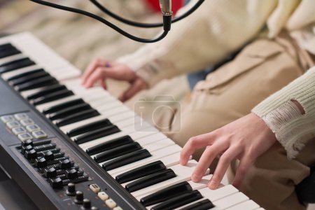 Téléchargez les photos : Main de jeune musicienne créative ou interprète sur les touches de synthétiseur électronique créant de la nouvelle musique tout en travaillant dans le home studio - en image libre de droit