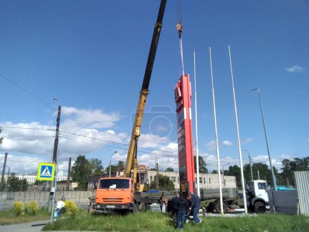 Foto de Sankt Petersburg Rusia - 05 30 2023 Instalación de un edificio de paneles de hormigón en una gasolinera. Dos trabajadores de la construcción conducen el panel. Enfoque selectivo. - Imagen libre de derechos