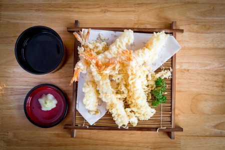Savourez les saveurs délicieuses du tempura de crevettes parfaitement frit servi sur un plat de bambou, complété par une sauce alléchante. Cette photographie culinaire haut de gamme capture l'essence de la cuisine asiatique.