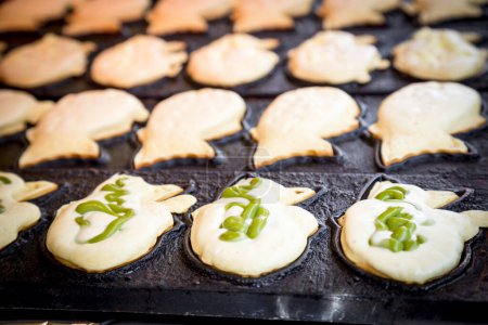 Delicious taiyaki: Fish-shaped pastry filled with red bean and green tea. A popular Japanese treat cooked on an iron pan.
