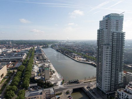 Photo for Brussels, Belgium - May 12, 2022: Urban landscape of the city of Brussels, skyscraper apartment building with the river Senne crossing Brussels and in the background the industries of the port - Royalty Free Image