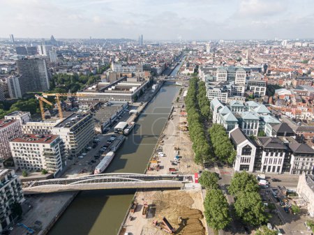 Foto de Bruselas, Bélgica 12 de mayo de 2022: Paisaje urbano de la ciudad de Bruselas. El canal del río Senne que cruza Bruselas y un puente para ciclistas y peatones en construcción. En el fondo el o - Imagen libre de derechos