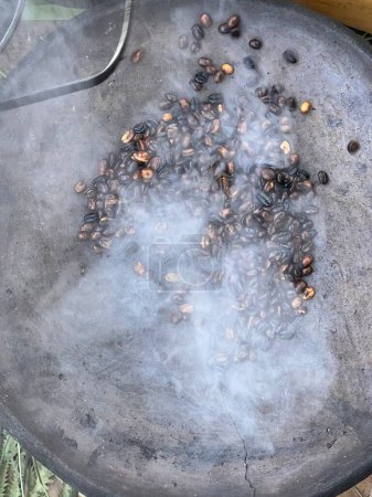 Photo for Coffee beans being roasted by hand in the traditional way on a wood-fired stove seen from above through the smoke - Royalty Free Image