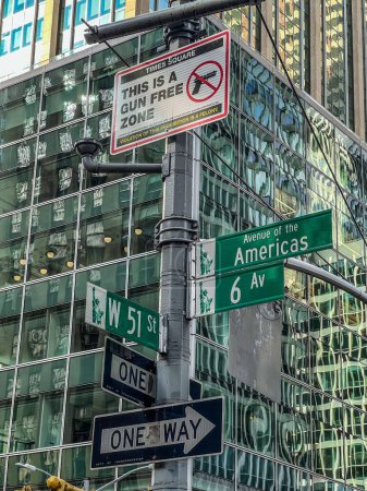 Panneaux de signalisation dans une rue de New York, y compris un panneau interdisant le port d'armes à feu dans la région. bâtiment en arrière-plan