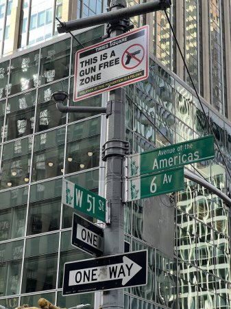 Señales de tráfico en una calle de Nueva York, incluyendo un cartel que prohíbe el transporte de armas en la zona. edificio en el fondo