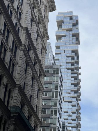 Foto de New-Yok, Estados Unidos, 16 de noviembre de 2023; Vista de un rascacielos moderno diseñado por el arquitecto Pavel Bendov, con la fachada de un antiguo edificio en primer plano en contraste. - Imagen libre de derechos