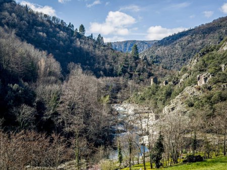 Scenic view of a tranquil Altier river  flowing through a lush valley with verdant forested hills and clear skies, Pied-de-Borne, Lozere, Cevenne, France, 
