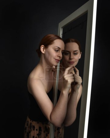 Photo for Close up portrait of beautiful girl looking into mirror, self reflection with colourful studio lighting. - Royalty Free Image