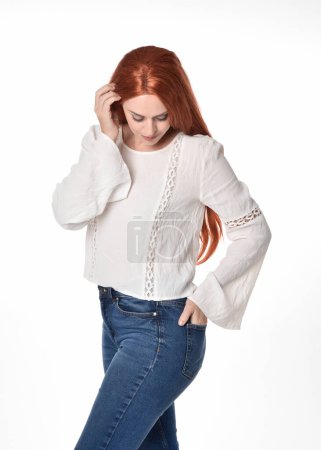 Photo for Close up portrait of beautiful woman model with long red hair, wearing casual outfit white blouse  top and denim jeans.  Posing with gestural arm poses, isolated on white studio background. - Royalty Free Image