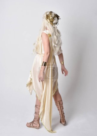 Photo for Full length portrait of beautiful blonde woman wearing a fantasy goddess toga costume with  magical crown.Standing pose, facing backwards away from camera.  isolated on white studio background. - Royalty Free Image