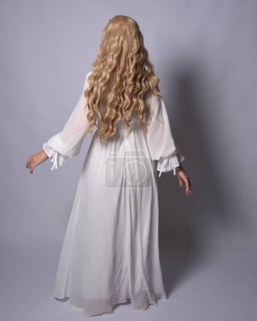 Photo for Full length portrait of blonde woman  wearing  white historical bridal gown fantasy costume dress. Standing pose, facing backwards walking away from camera, isolated on studio background. - Royalty Free Image