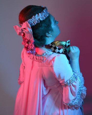 Foto de Retrato de modelo femenina con un vestido rosa opulento, traje de una nobleza barroca francesa histórica, estilo de María Antonieta. Aislado en el fondo del estudio cinemático iluminación colorida - Imagen libre de derechos