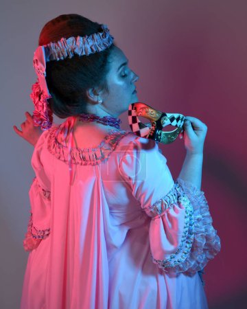 Photo for Portrait of female model wearing an opulent pink gown,  costume of a historical French baroque nobility, style of Marie Antoinette. Isolated on  studio background cinematic  colourful lighting - Royalty Free Image