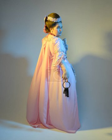 Photo for Cinematic  portrait of female model wearing an opulent pink gown,  costume of a historical French baroque nobility, style of Marie Antoinette. Holding ring of keys,  Isolated on  studio background - Royalty Free Image