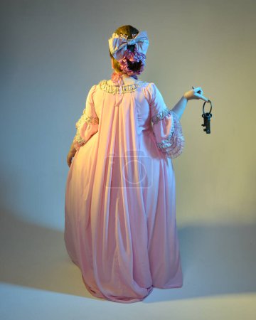 cinematic  portrait of female model wearing an opulent pink gown,  costume of a historical French baroque nobility, style of Marie Antoinette. Holding ring of keys,  Isolated on  studio background