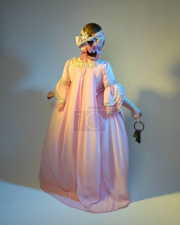 Foto de Retrato cinematográfico de la modelo femenina con un vestido rosa opulento, traje de una nobleza barroca francesa histórica, estilo de María Antonieta. Anillo de sujeción de llaves, aislado en el fondo del estudio - Imagen libre de derechos