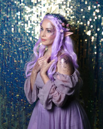 Photo for Portrait of cute female model with long purple hair wearing a fantasy fairy flower crown with elf ears. Isolated on sparkling rainbow sequin background with glitter. - Royalty Free Image
