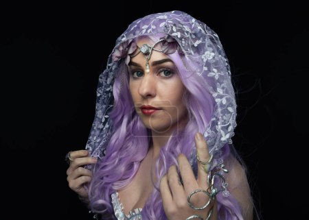 Photo for Artistic portrait of beautiful female model with long purple hair wearing a flowing fantasy cloak.  isolated on dark studio background. - Royalty Free Image