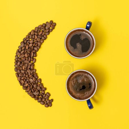 Foto de Dos tazas de café y un emoticono hecho de granos de café sobre un fondo amarillo, lugar para texto y espacio de copia. - Imagen libre de derechos