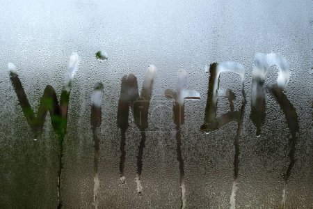 Foto de El invierno de la inscripción se pinta en el vidrio con la condensación, el efecto de las ventanas empañadas y el vidrio, gota de agua clara realista, gotas de agua para el diseño creativo de la bandera - Imagen libre de derechos