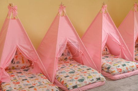 Foto de Cunas en el jardín de infantes para siestas en forma de tiendas de campaña, colores brillantes de los muebles de los niños. - Imagen libre de derechos