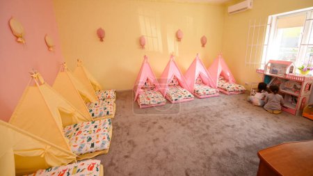 Foto de Cunas en el jardín de infantes para siestas en forma de tiendas de campaña, colores brillantes de los muebles de los niños. - Imagen libre de derechos
