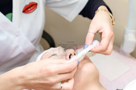 Téléchargez les photos : Removing a moisturizing mask from the face in a cosmetology office, cosmetology procedures in a spa salon. - en image libre de droit