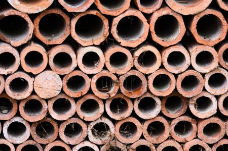 Téléchargez les photos : Drainage de vieux tuyaux d'argile pour les eaux usées empilés dans une texture avec des trous de fermeture - en image libre de droit