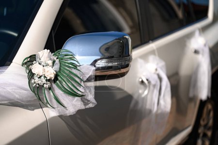 Foto de Un coche blanco en el que el espejo y las manijas de la puerta están decoradas con flores, un coche para bodas - Imagen libre de derechos