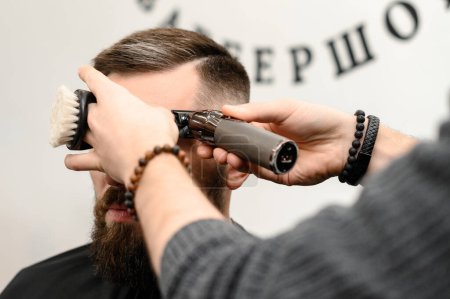 Foto de Corte de pelo y alineación del contorno de la cabeza con un cortador de pelo y recortador. Corte de pelo corto en la peluquería. - Imagen libre de derechos