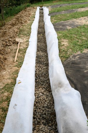 Photo for The drainage trench is covered with geotextile and filled with crushed stone to drain ground water from the site and adjacent territory - Royalty Free Image
