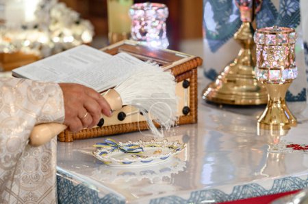 Téléchargez les photos : Le prêtre asperge la croix d'or d'eau bénite, rites chrétiens dans l'église. - en image libre de droit