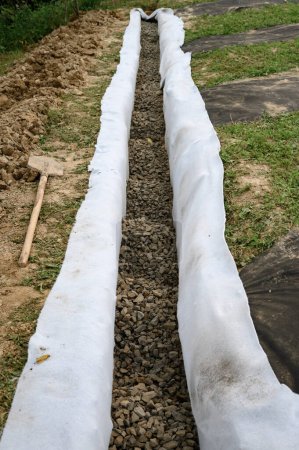 Photo for The drainage trench is covered with geotextile and filled with crushed stone to drain ground water from the site and adjacent territory - Royalty Free Image