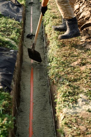Téléchargez les photos : Un plombier installe un tuyau d'égout orange renforcé lors de l'entretien du site. - en image libre de droit