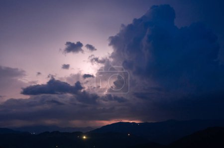 Photo for An evening thunderstorm with lightning in the Carpathian mountains, the village of Dzembronya. Dramatic clouds during a thunderstorm pierce the light of lightning in a mountainous area. - Royalty Free Image
