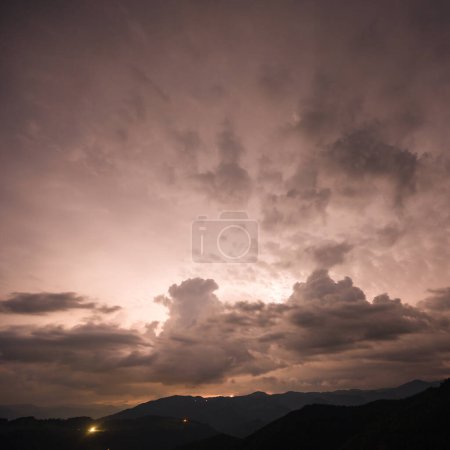 Ein abendliches Gewitter mit Blitz in den Karpaten, dem Dorf Dzembronya. Dramatische Wolken während eines Gewitters durchdringen das Licht des Blitzes in einer bergigen Region.