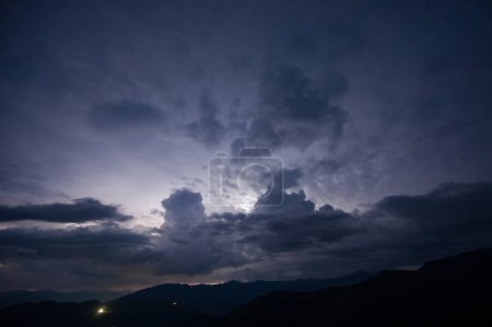 An evening thunderstorm with lightning in the Carpathian mountains, the village of Dzembronya. Dramatic clouds during a thunderstorm pierce the light of lightning in a mountainous area.
