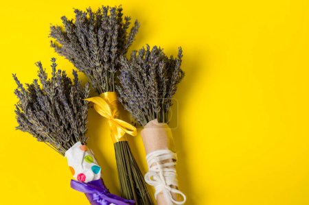 Three bouquets of dried lavender on a yellow background, lavender is a cosmetic plant.